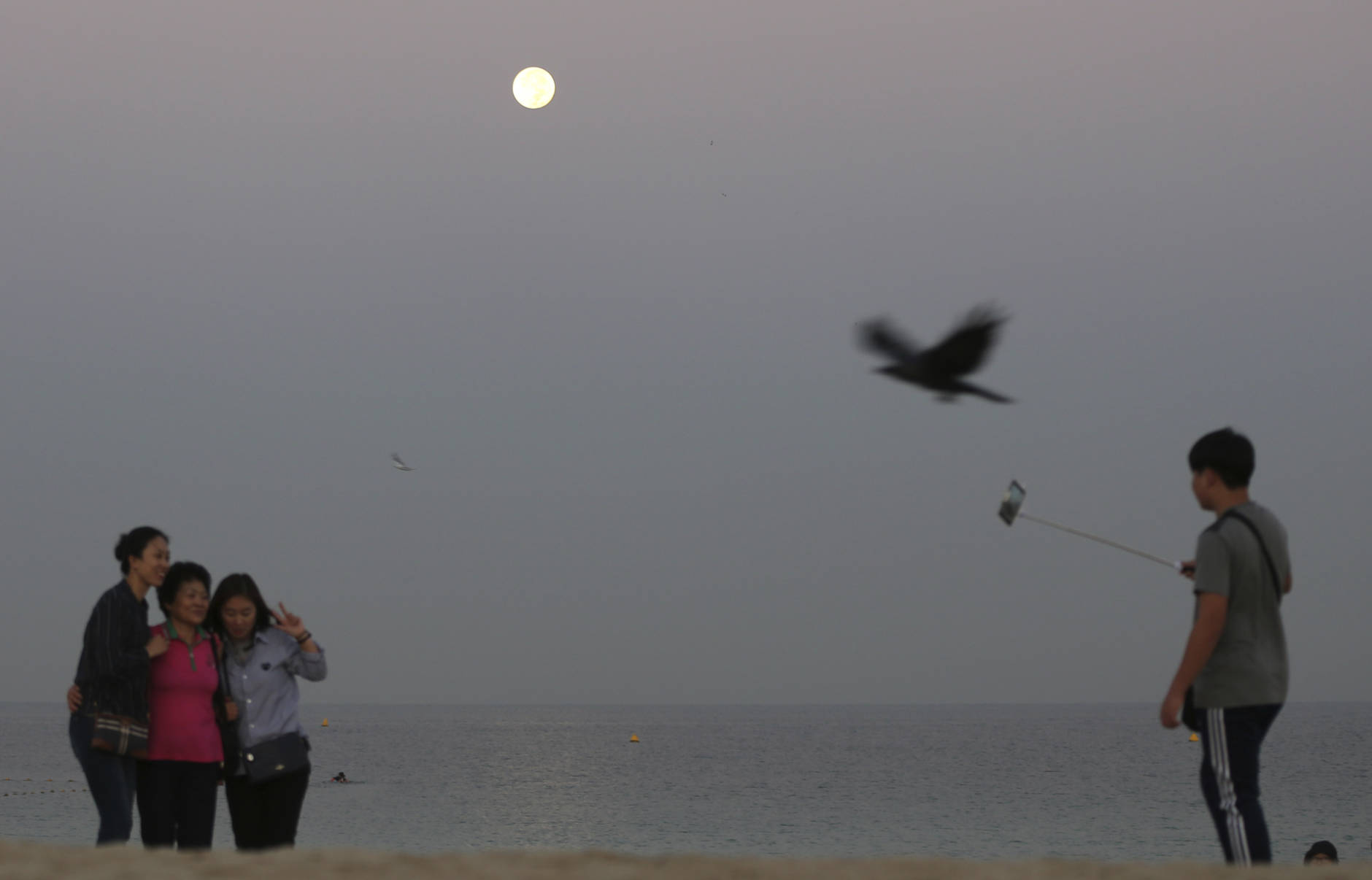 Korean tourists pose for a photo as they come to watch the supermoon at the Jumeirah beach in Dubai, United Arab Emirates, Tuesday, Nov. 15, 2016. (AP Photo/Kamran Jebreili)