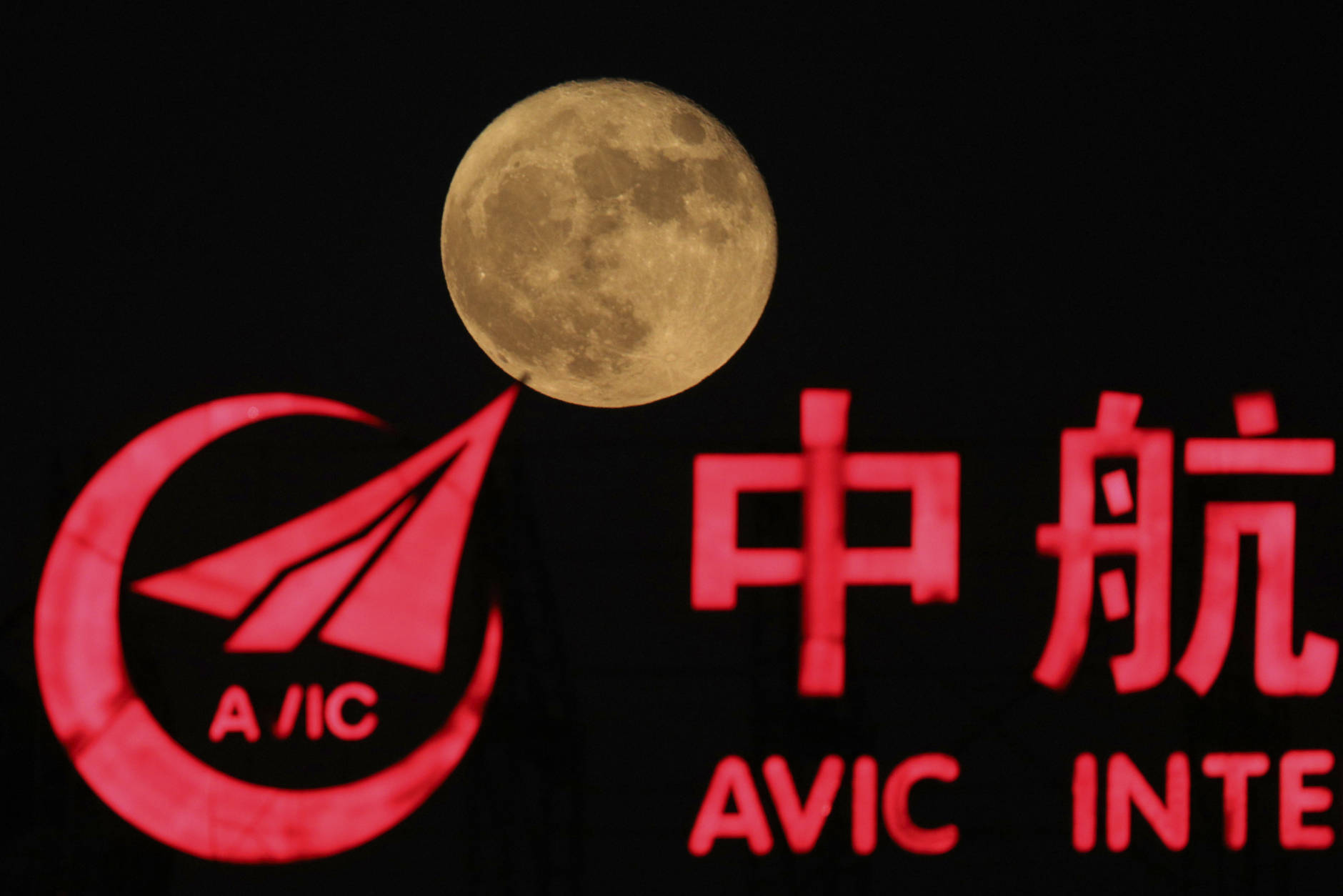 The supermoon, rises over a logo for AVIC or Aviation Industry Corp in Beijing, China, Tuesday, Nov. 15, 2016. AVIC is a Chinese state-owned corporate colossus with 500,000 employees and 140 subsidiaries in businesses ranging from aircraft manufacturing, financial services, auto production and contributing to China's manned space flights. (AP Photo/Ng Han Guan)