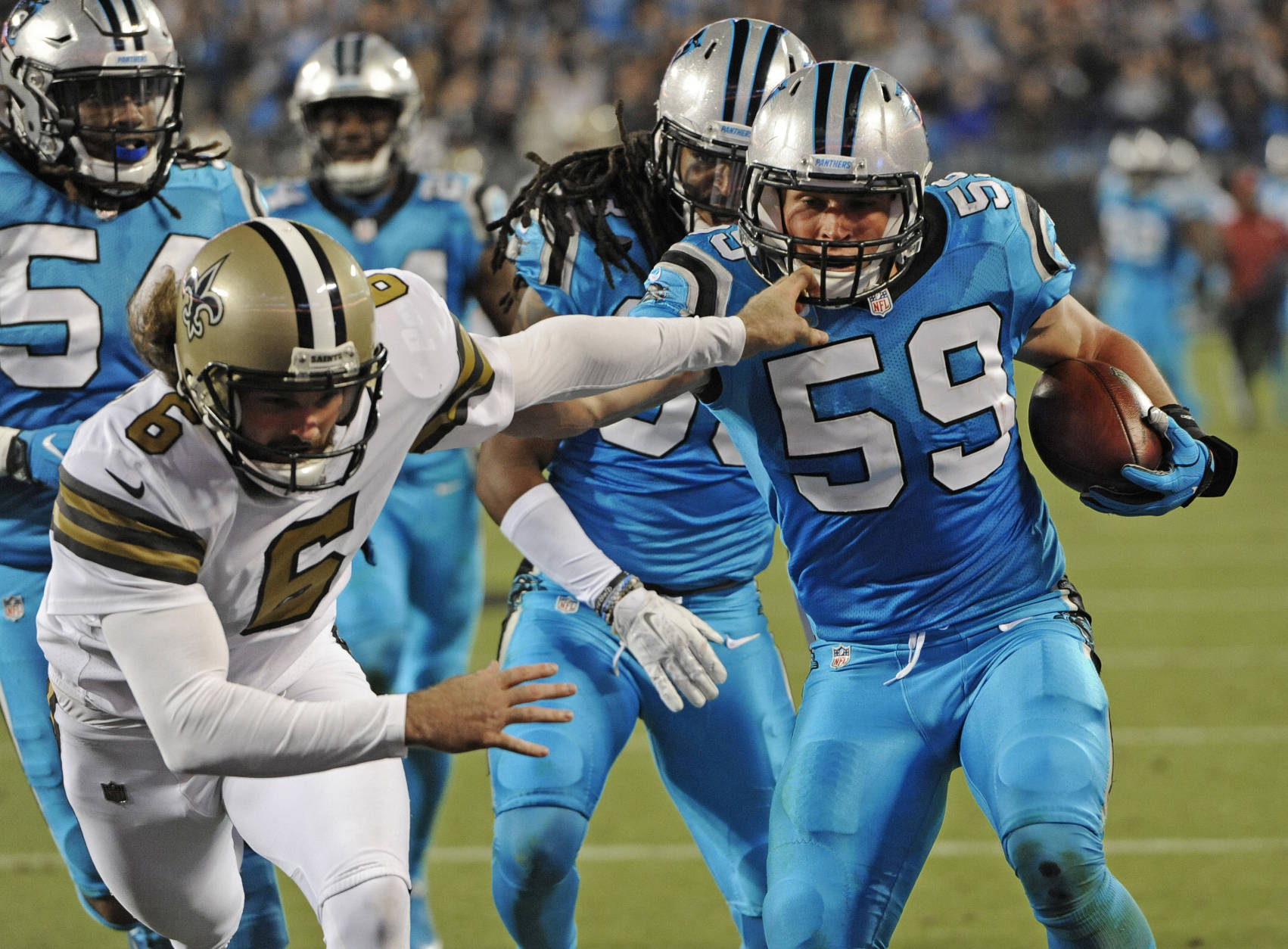 Carolina Panthers' Luke Kuechly (59) runs past New Orleans Saints' Thomas Morstead (6) as he returns a blocked field goal attempt in the first half of an NFL football game in Charlotte, N.C., Thursday, Nov. 17, 2016. (AP Photo/Mike McCarn)