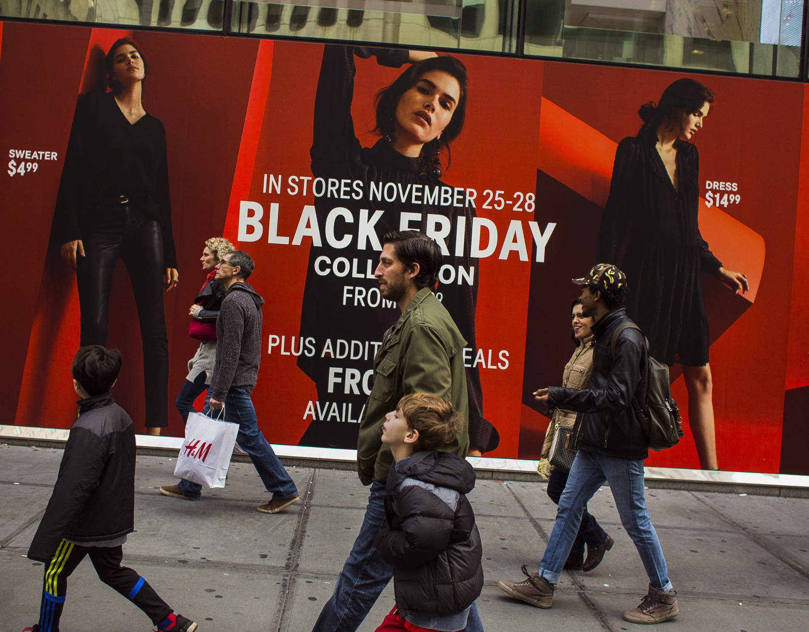 Shoppers pass by a retail store as they walk along Fifth Avenue on Black Friday in New York, Friday, Nov. 25, 2016. (AP Photo/Andres Kudacki)