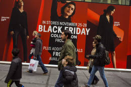Shoppers pass by a retail store as they walk along Fifth Avenue on Black Friday in New York, Friday, Nov. 25, 2016. (AP Photo/Andres Kudacki)