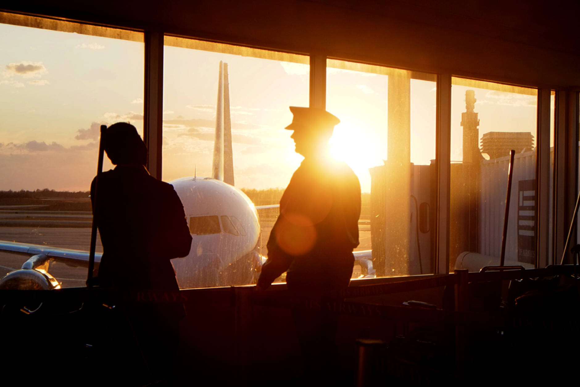 An airline pilot talks with a crew member between flights as the sun sets at the Charlotte Douglas International Airport in Charlotte, N.C., Friday Jan. 18, 2014. (AP Photo/J. David Ake)
