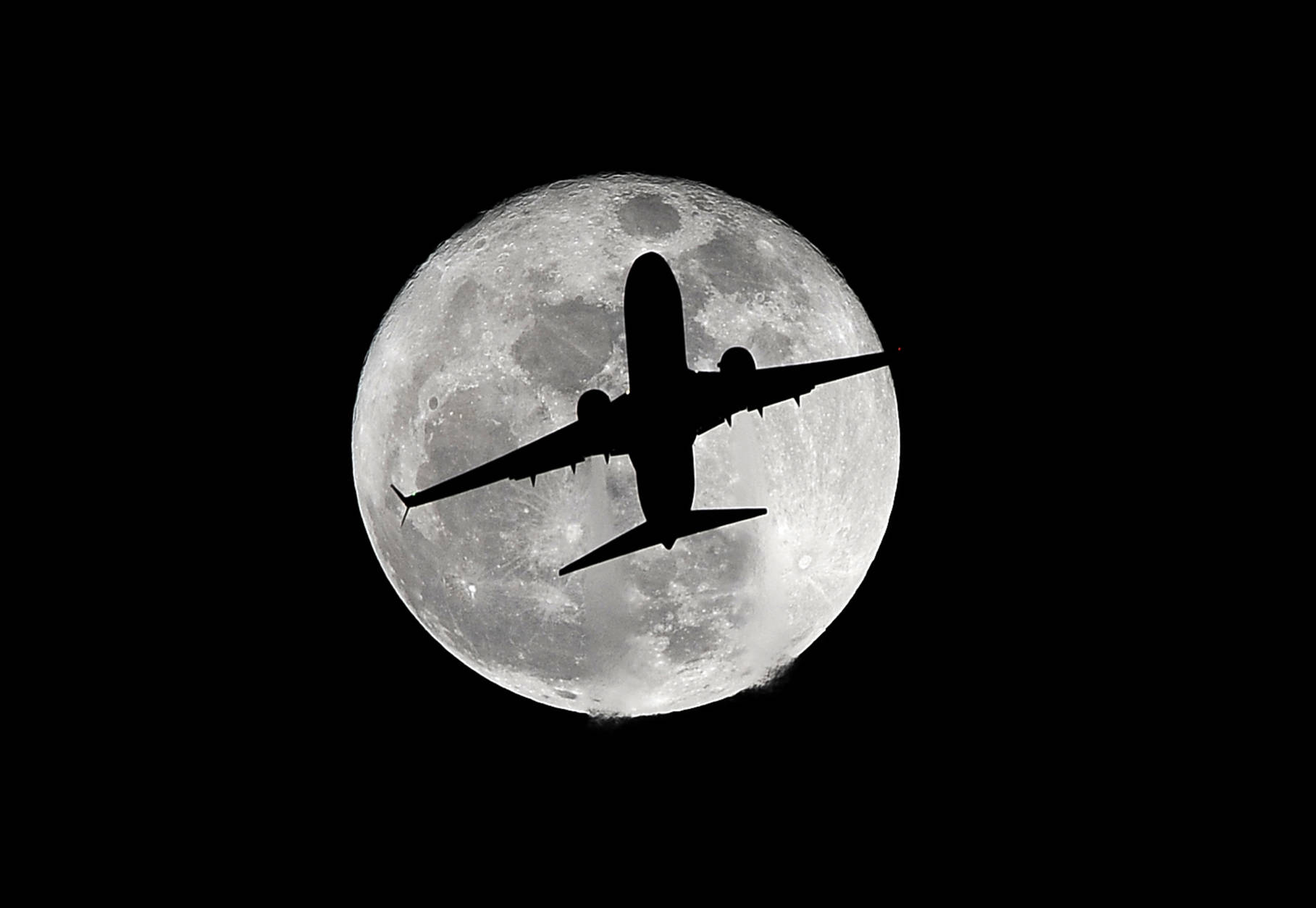 A passenger plane heading to Los Angeles International Airport passes by the supermoon Monday, Nov. 14, 2016. The phenomenon known as the supermoon occurs because the moon follows an elliptical orbit around the Earth. This week, the moon is coming closer to the Earth than at any time since January 1948. (AP Photo/Nick Ut)