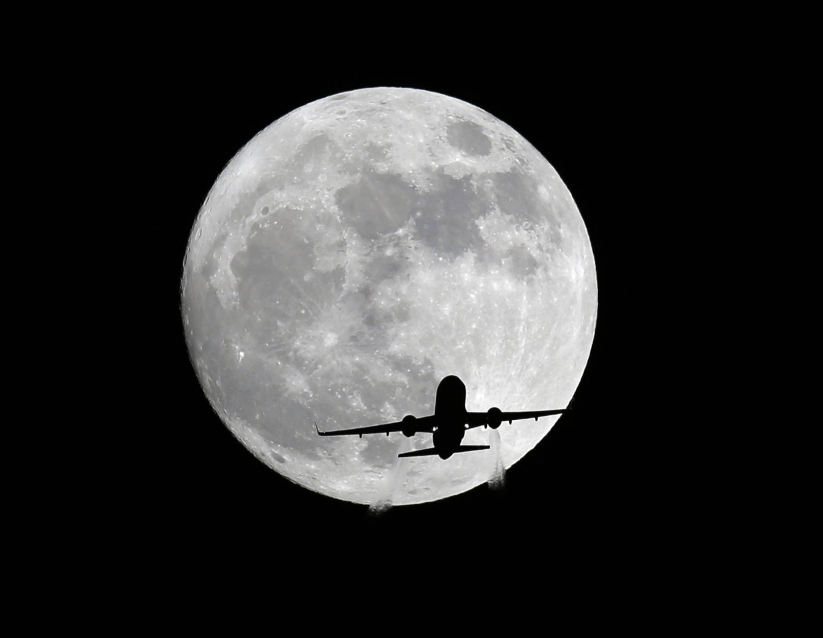 An American Airlines passenger plane passes in front of the moon, as seen from Whittier, Calif., Sunday, Nov. 13, 2016. Monday morning's supermoon will be the closet a full moon has been to the Earth since Jan. 26, 1948. (AP Photo/Nick Ut)