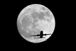 An American Airlines passenger plane passes in front of the moon, as seen from Whittier, Calif., Sunday, Nov. 13, 2016. Monday morning's supermoon will be the closet a full moon has been to the Earth since Jan. 26, 1948. (AP Photo/Nick Ut)