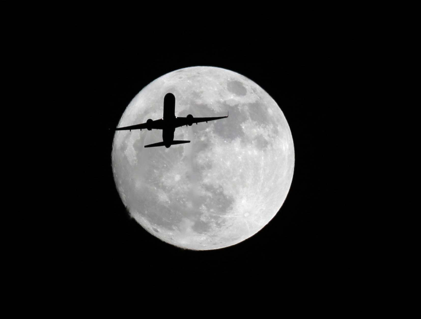 An American Airlines passenger plane passes in front of the moon, as seen from Whittier, Calif., Sunday, Nov. 13, 2016. Monday morning's supermoon will be the closet a full moon has been to the Earth since Jan. 26, 1948. (AP Photo/Nick Ut)