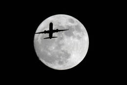 An American Airlines passenger plane passes in front of the moon, as seen from Whittier, Calif., Sunday, Nov. 13, 2016. Monday morning's supermoon will be the closet a full moon has been to the Earth since Jan. 26, 1948. (AP Photo/Nick Ut)