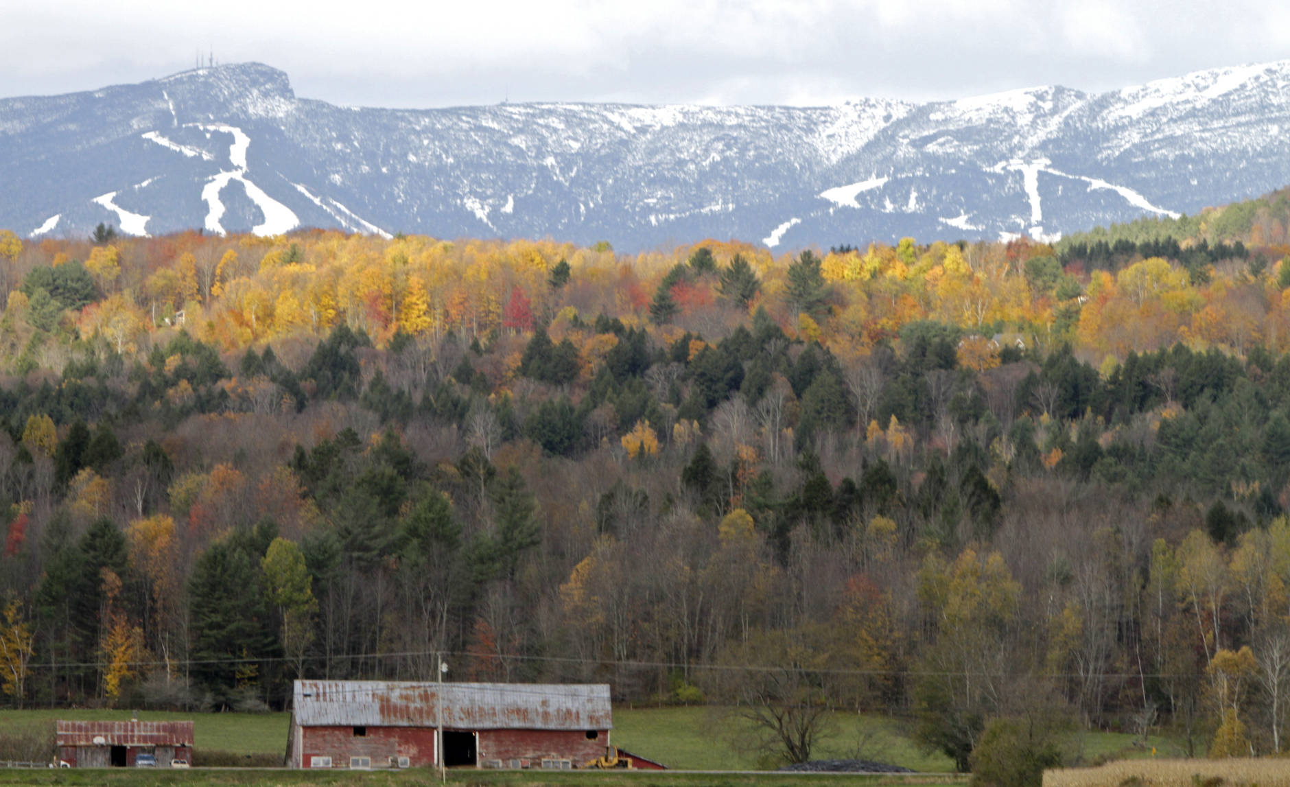 FILE-In this Oct. 18, 2010, file photo, sunlight falls on remaining bright foliage as the snow capped ski trails of Stowe ski resort are seen on the side of Mt. Mansfield in Stowe , Vt. Mountain and lake views along with fall foliage can be had for free in Vermont's largest city of Burlington, which feels more like a big town than a city. (AP Photo/Toby Talbot)