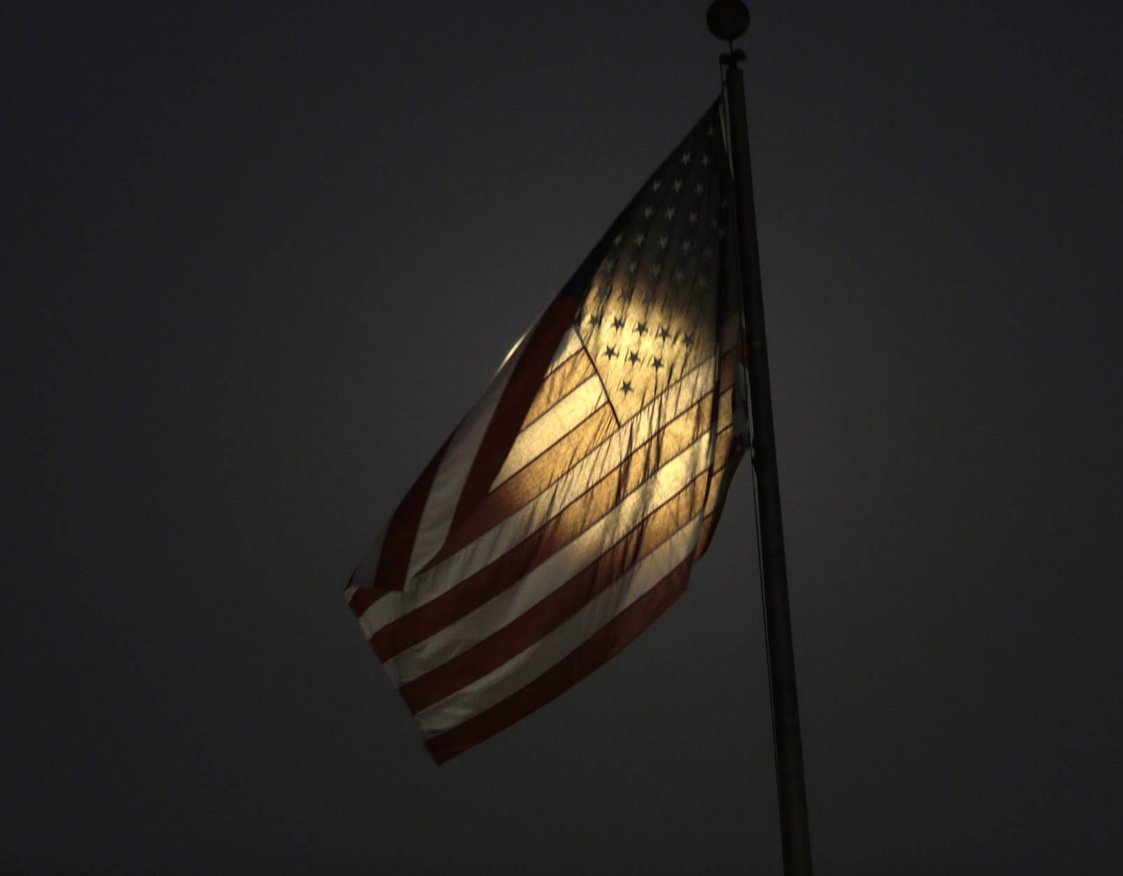 Light from the moon shines through a U.S. flag in South El Monte, Calif., Sunday, Nov. 13, 2016. Monday morning's supermoon will be the closet a full moon has been to the Earth since Jan. 26, 1948. (AP Photo/Nick Ut)