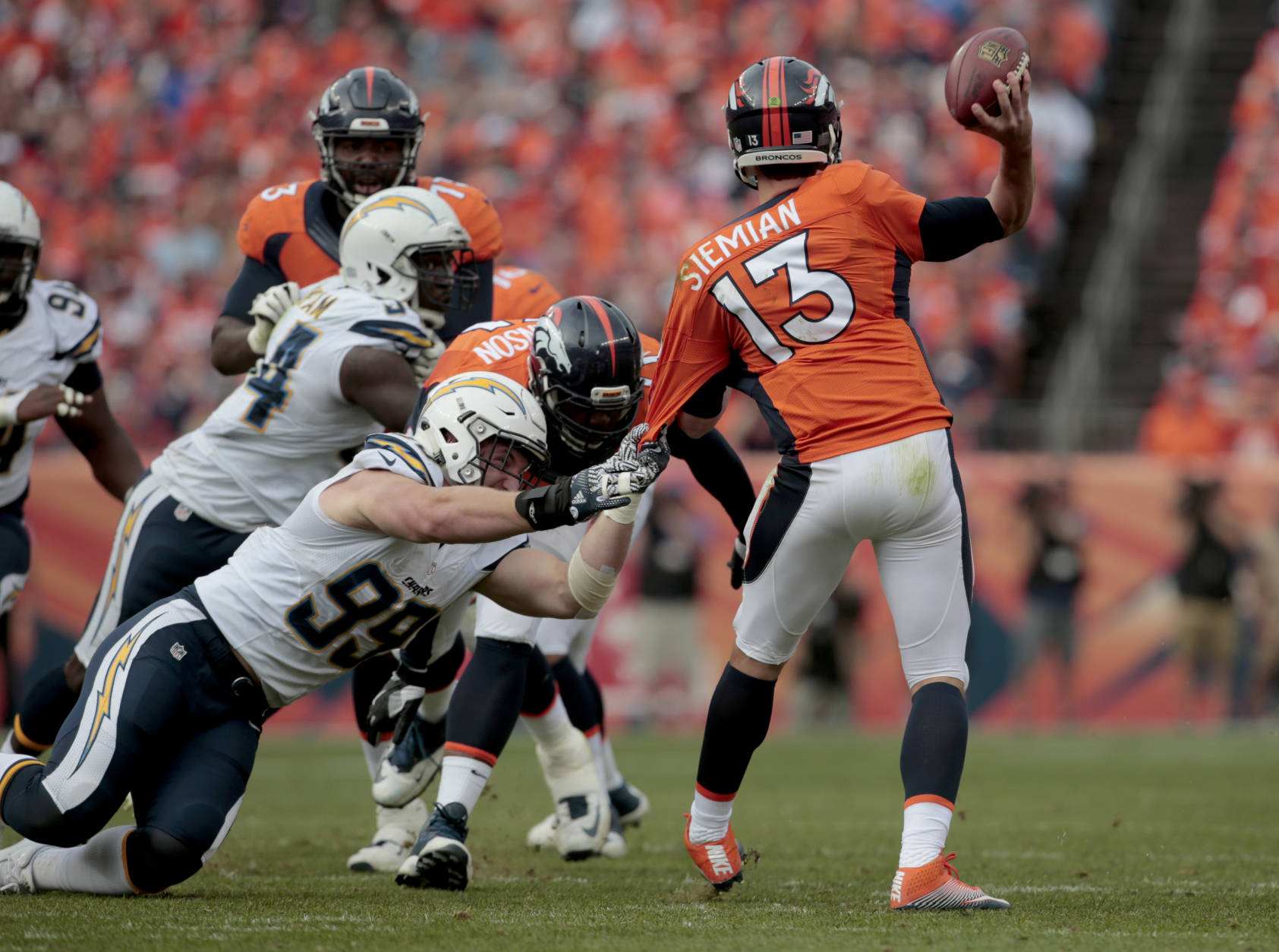 Denver Broncos quarterback Trevor Siemian (13) is pulled down by San Diego Chargers defensive end Joey Bosa (99) during the first half of an NFL football game, Sunday, Oct. 30, 2016, in Denver. (AP Photo/Joe Mahoney)