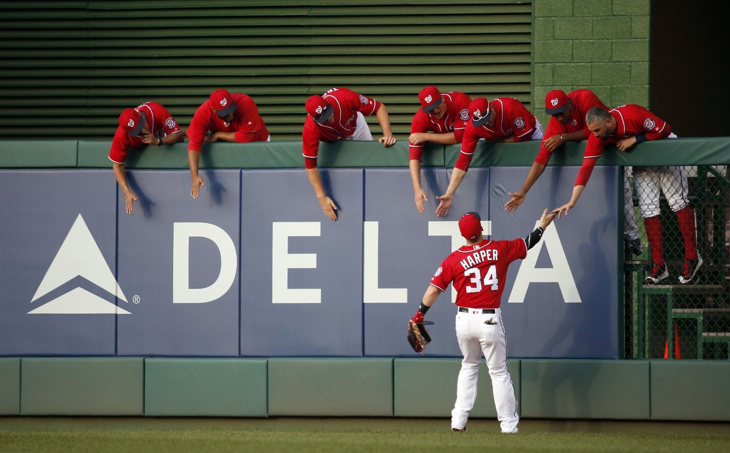 Washington Nationals right fielder Bryce Harper (34) greets his teammates in the bullpen as he heads to right field for the first inning of a baseball game against the St. Louis Cardinals at Nationals Park, Saturday, May 28, 2016, in Washington. (AP Photo/Alex Brandon)