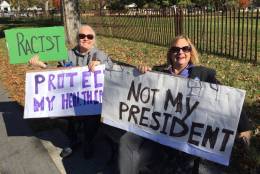 Julie Klinkner of Gaithersburg and Michele LaBar of Rockville protest at the White House Thursday. (WTOP/Kristi King)