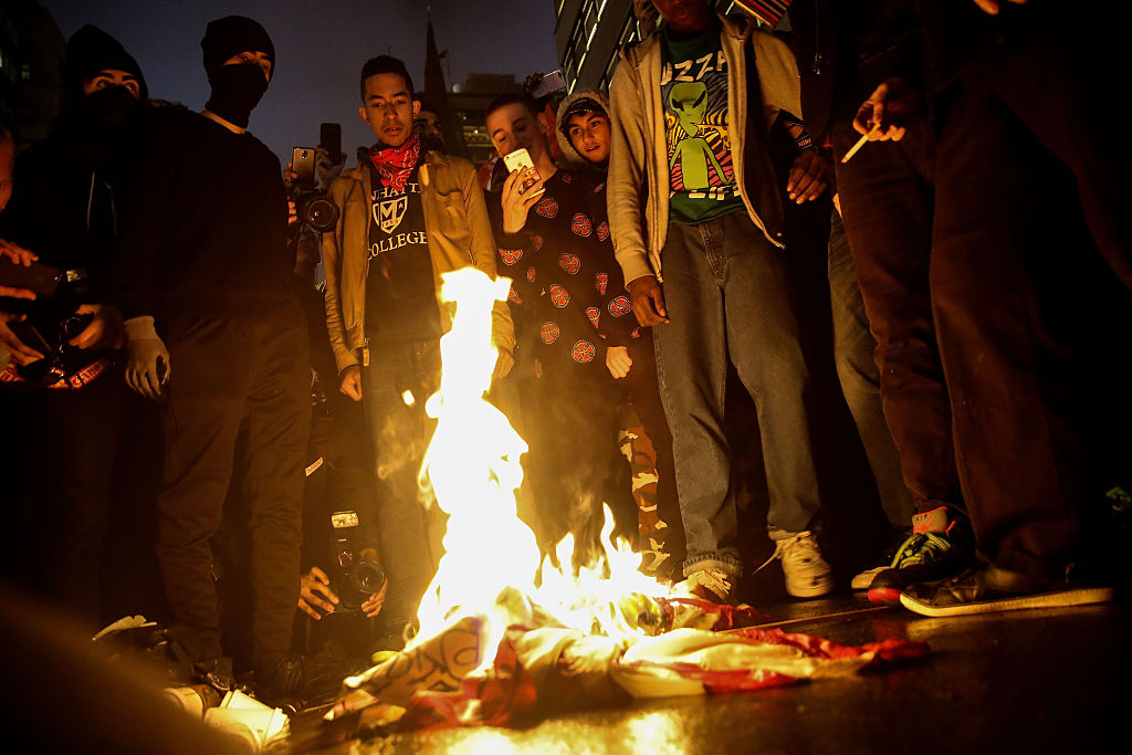 NEW YORK, NY - NOVEMBER 9: Protestors burn an American flag on Fifth Avenue outside of Trump Tower, November 9, 2016 in New York City. Republican candidate Donald Trump won the 2016 presidential election in the early hours of the morning in a widely unforeseen upset. (Photo by Drew Angerer/Getty Images)