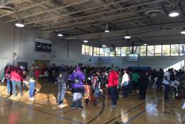 Tables were aligned in rows in a gymnasium with volunteers for Northern Virginia Project Giveback on either side filling boxes with food as they moved down the line Saturday, Nov. 16, 2016 in Alexandria, Virginia. (WTOP/Dennis Foley)