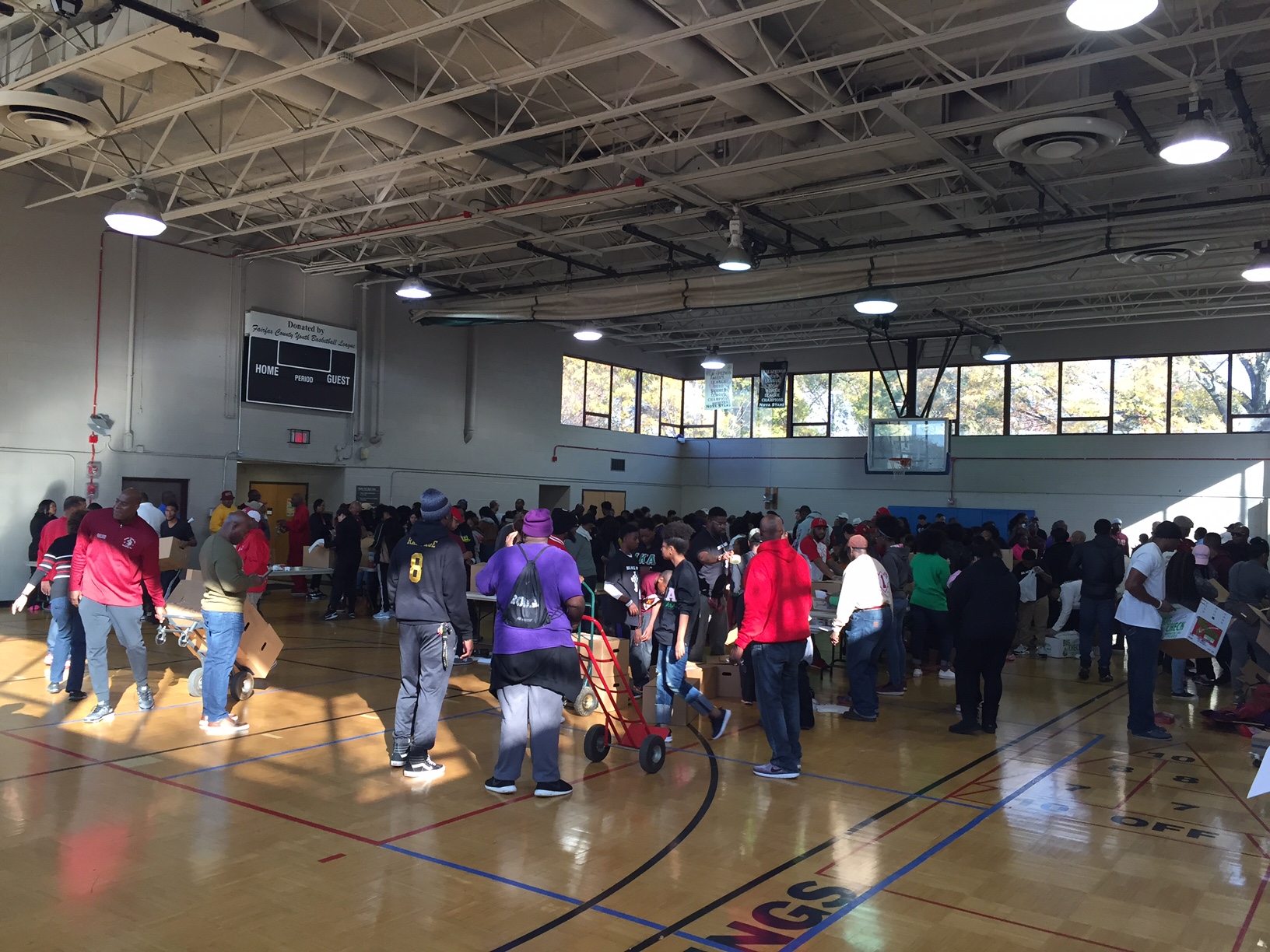 Tables were aligned in rows in a gymnasium with volunteers for Northern Virginia Project Giveback on either side filling boxes with food as they moved down the line Saturday, Nov. 16, 2016 in Alexandria, Virginia. (WTOP/Dennis Foley)