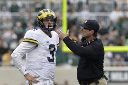 Michigan head coach Jim Harbaugh talks with quarterback Wilton Speight (3) during the first half of an NCAA college football game against Michigan State, Saturday, Oct. 29, 2016, in East Lansing, Mich. (AP Photo/Carlos Osorio)