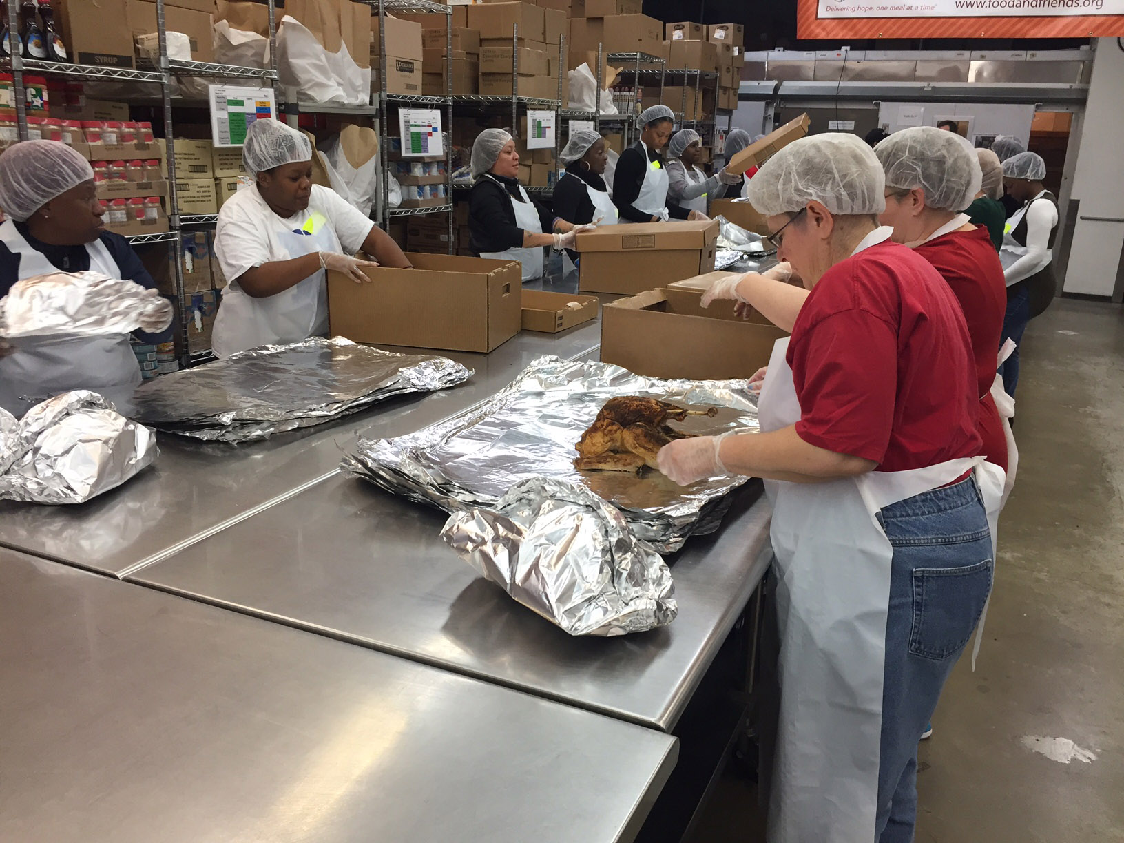 Volunteers pack meals for 3,500 people at Food &amp; Friends in Northeast D.C. on Thursday morning. More than 450 volunteers will help prepare and deliver the Thanksgiving meals to those suffering from chronic illnesses like cancer and HIV. (WTOP/John Domen)