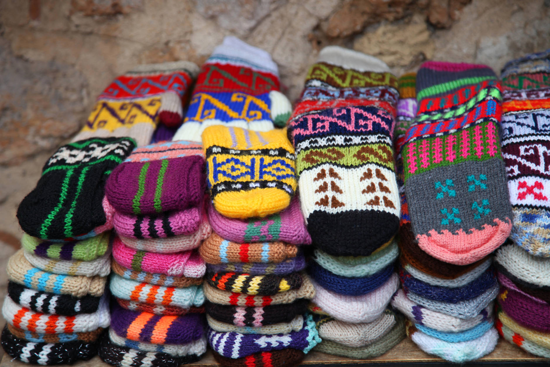 Bright mittens and socks with an ornament on a background of a stone wall