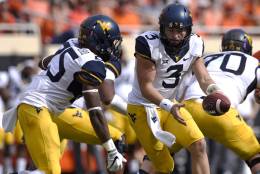 FILE - In this Oct. 29, 2016, file photo, West Virginia quarterback Skyler Howard (3) hands off to running back Justin Crawford during the team's NCAA college football game against Oklahoma State in Stillwater, Okla. West Virginia travels to play Texas this week. (AP Photo/Brody Schmidt, File)