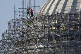 Workmen are seen taking apart the scaffolding that has shrouded the Capitol Dome for two years as it received a multi-million dollar renovation to repair cracks, remove lead paint and restore the structure to its original splendor, in Washington, Monday, March 21, 2016. (AP Photo/J. Scott Applewhite)