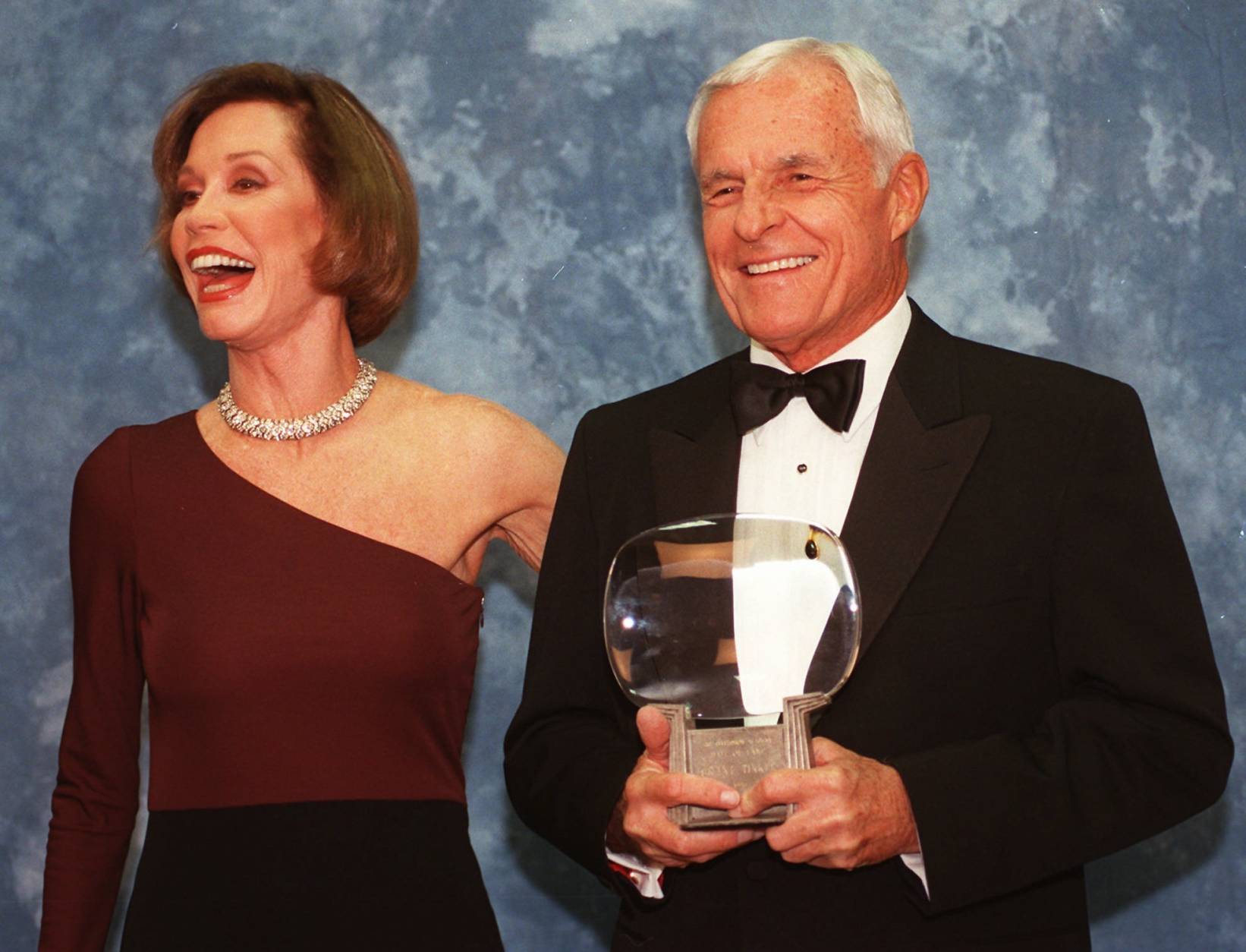 FILE - In this Saturday, Nov. 1, 1997, file photo, Television executive Grant Tinker holds up his Hall of Fame award alongside his ex-wife Mary Tyler Moore at the Academy of Television Arts &amp; Sciences' 13th Annual Hall of Fame induction ceremonies in the North Hollywood section of Los Angeles. Tinker, who brought "The Mary Tyler Moore Show" and other hits to the screen as a producer and a network boss, has died. Tinker died Monday, Nov. 28, 2016, at his home in Los Angeles, according to his son, Mark Tinker. (AP Photo/Chris Pizzello, File)