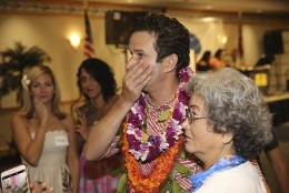 While standing with supporters, U.S. Sen. Brian Schatz, center, looks over at a television showing election results at the Japanese Community Center, Tuesday, Nov. 8, 2016, in Honolulu. (AP Photo/Marco Garcia)