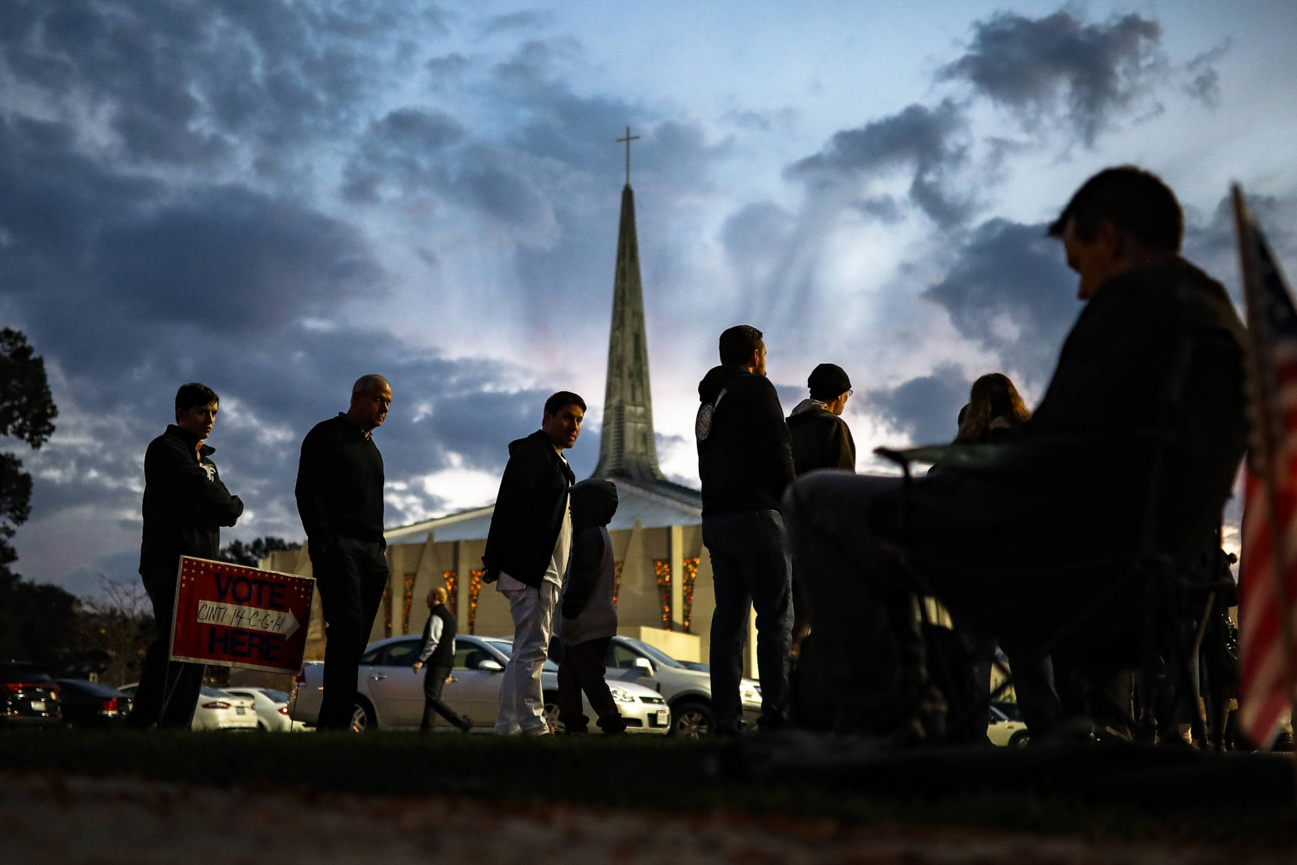 Adam Fohlen, his son Ari, center left, and others, wait in line outside a polling place at the Nativity School as a poll watcher sits nearby, Tuesday, Nov. 8, 2016, in Cincinnati. (AP Photo/John Minchillo)