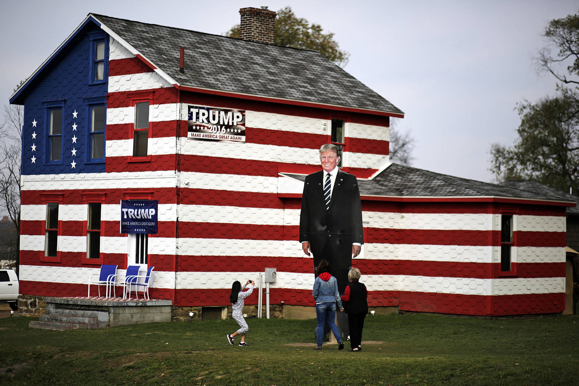 A young visitor takes a photo of a giant cutout of Republican candidate for president Donald Trump in front of the Trump House owned by Lisa Rossi in Youngstown, Pa, Tuesday, Nov. 8, 2016. (AP Photo/Gene J. Puskar)
