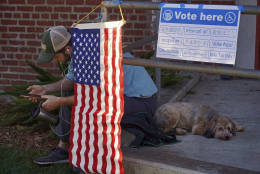 Scott McCabe sits with his dog Steve outside a polling station after voting in the Echo Park neighborhood of Los Angeles, Tuesday, Nov. 8, 2016. Los Angeles County is currently required to provide the following language assistance for the minority language provisions of the Voting Rights Act (VRA) of 1965 voters, in addition to English: Chinese, Hindi, Japanese, Cambodian/Khmer, Korean, Spanish, Tagalog/Filipino, Thai, Vietnamese. (AP Photo/Damian Dovarganes)