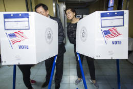 Nancy Liu, right, watches her husband John Liu, center, as he is helped by a Chinese translator, left, at a polling station in Flushing, the Queens borough of New York, Tuesday, Nov. 8, 2016. Born in Taiwan, John and Nancy immigrated to the United States 38 years ago, and this is their first time voting. (AP Photo/Alexander F. Yuan)