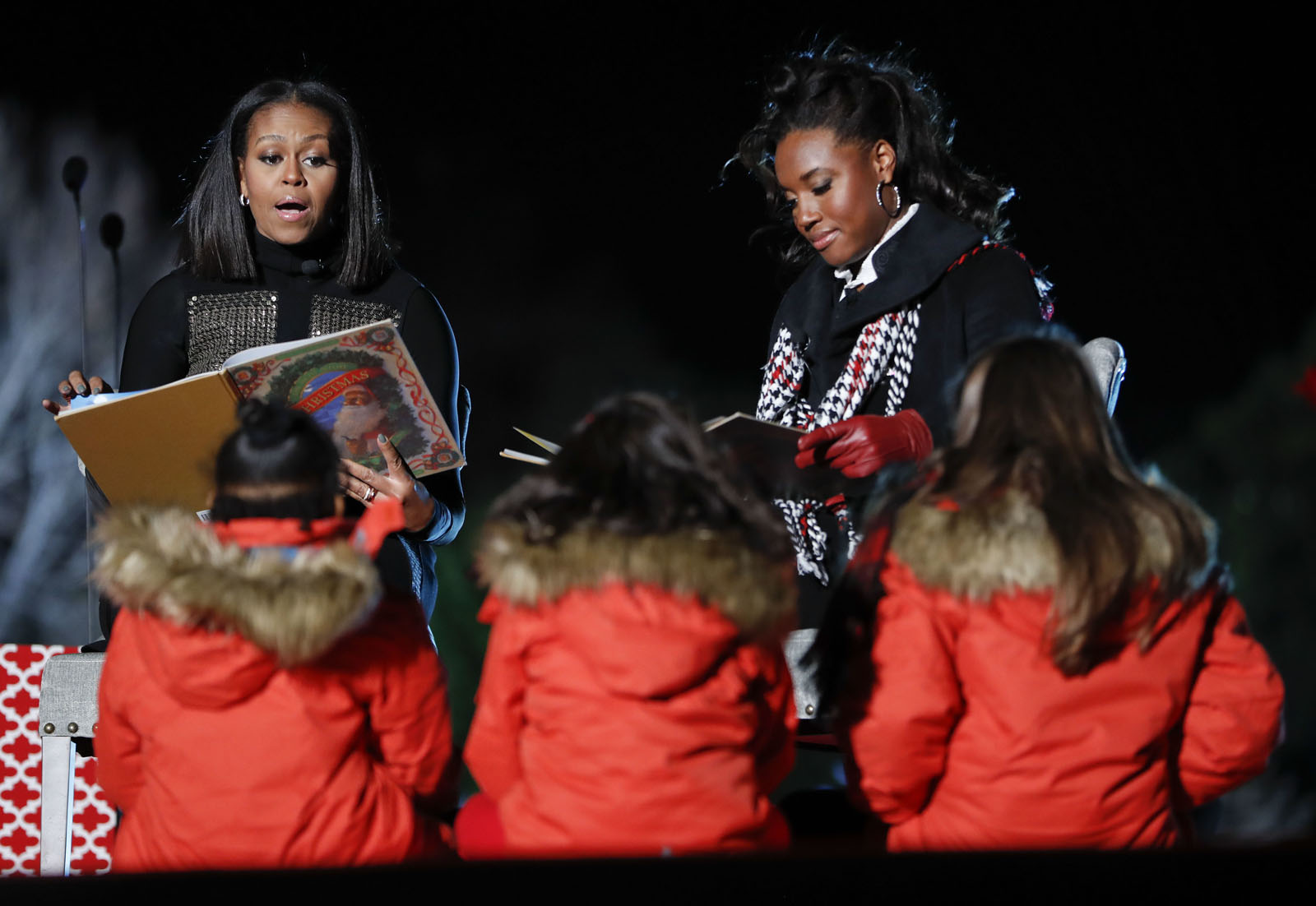 First lady Michelle Obama, left, and Olympic medal winner Simone Manuel, right, read "Twas The Night Before Christmas" to children on stage during the 2016 National Christmas Tree lighting ceremony at the Ellipse near the White House in Washington, Thursday, Dec. 1, 2016. (AP Photo/Pablo Martinez Monsivais)