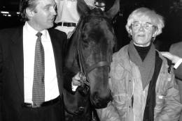 Donald Trump owner of New York's Trump Tower, holds the bridle of a polo pony while talking to Andy Warhol on Nov. 4, 1983.  Yale University polo player Eric Stever sits astride the horse.  (AP Photo/Mario Suriani)