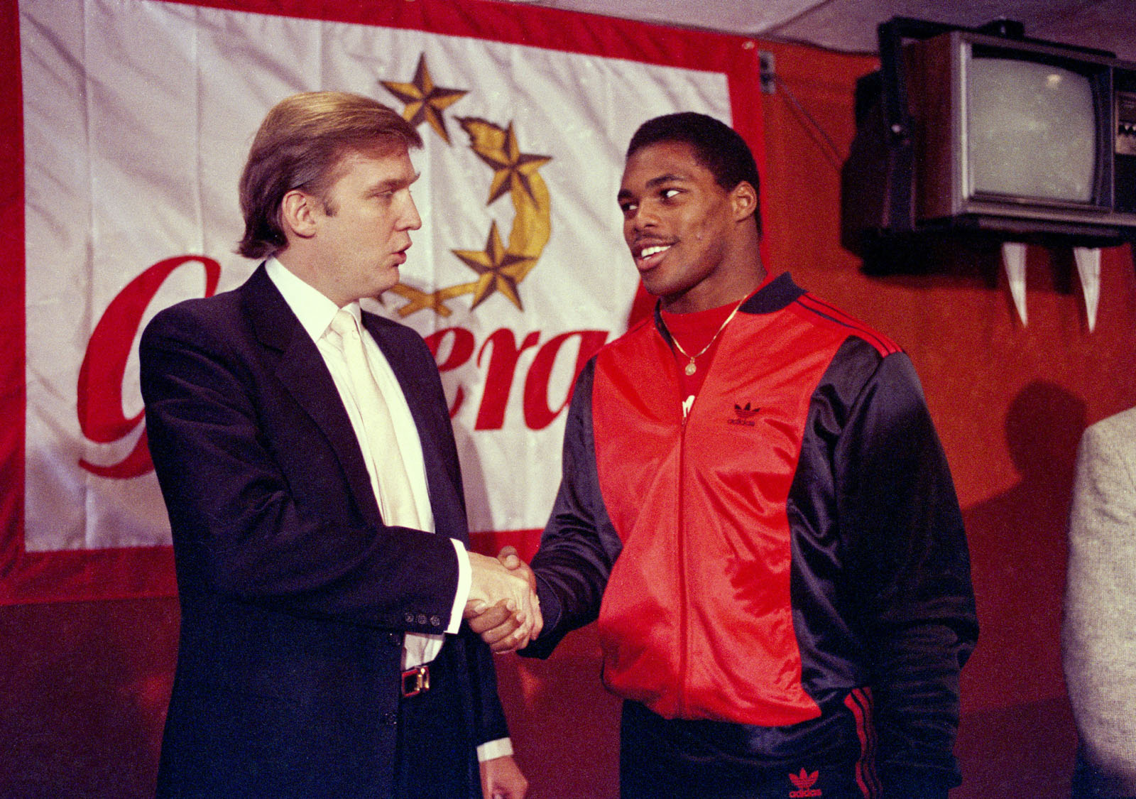 FILE - In this March 8, 1984, file photo, then-New Jersey Generals owner Donald Trump, left, shakes hands with Herschel Walker at a press conference in New York, after agreeing on a 4-year contract. Retired NFL player Herschel Walker says he's being dropped from speaking engagements because of his relationship with Donald Trump. (AP Photo/Dave Pickoff, File)