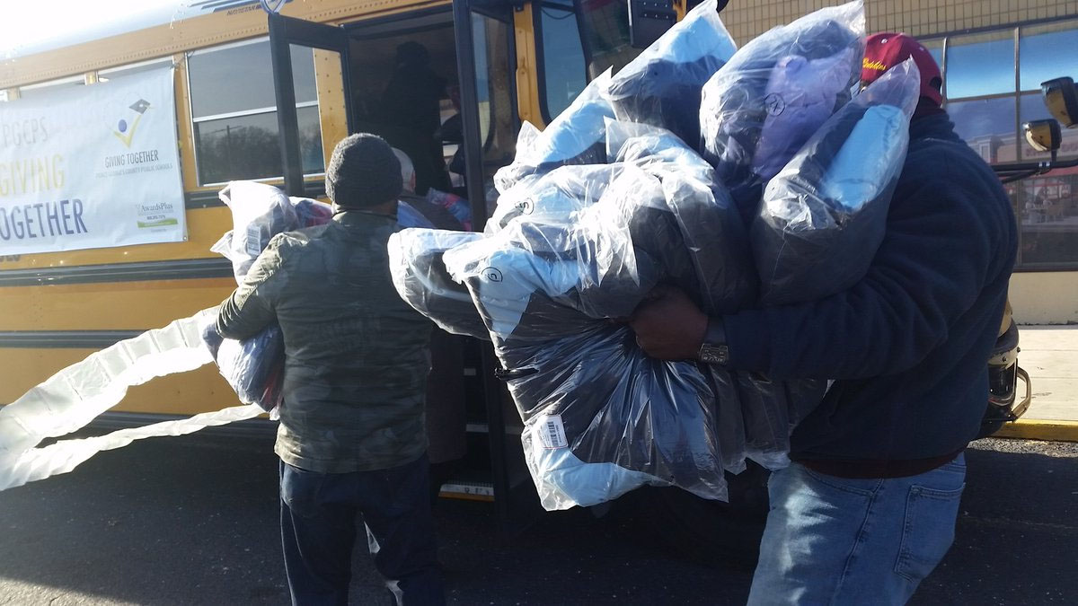 Volunteers and Prince George's County Public Schools CEO Kevin Maxwell loaded up a school bus with new coats for more than 300 homeless students. The coats were donated by the Shops at Iverson. (WTOP/Kathy Stewart)