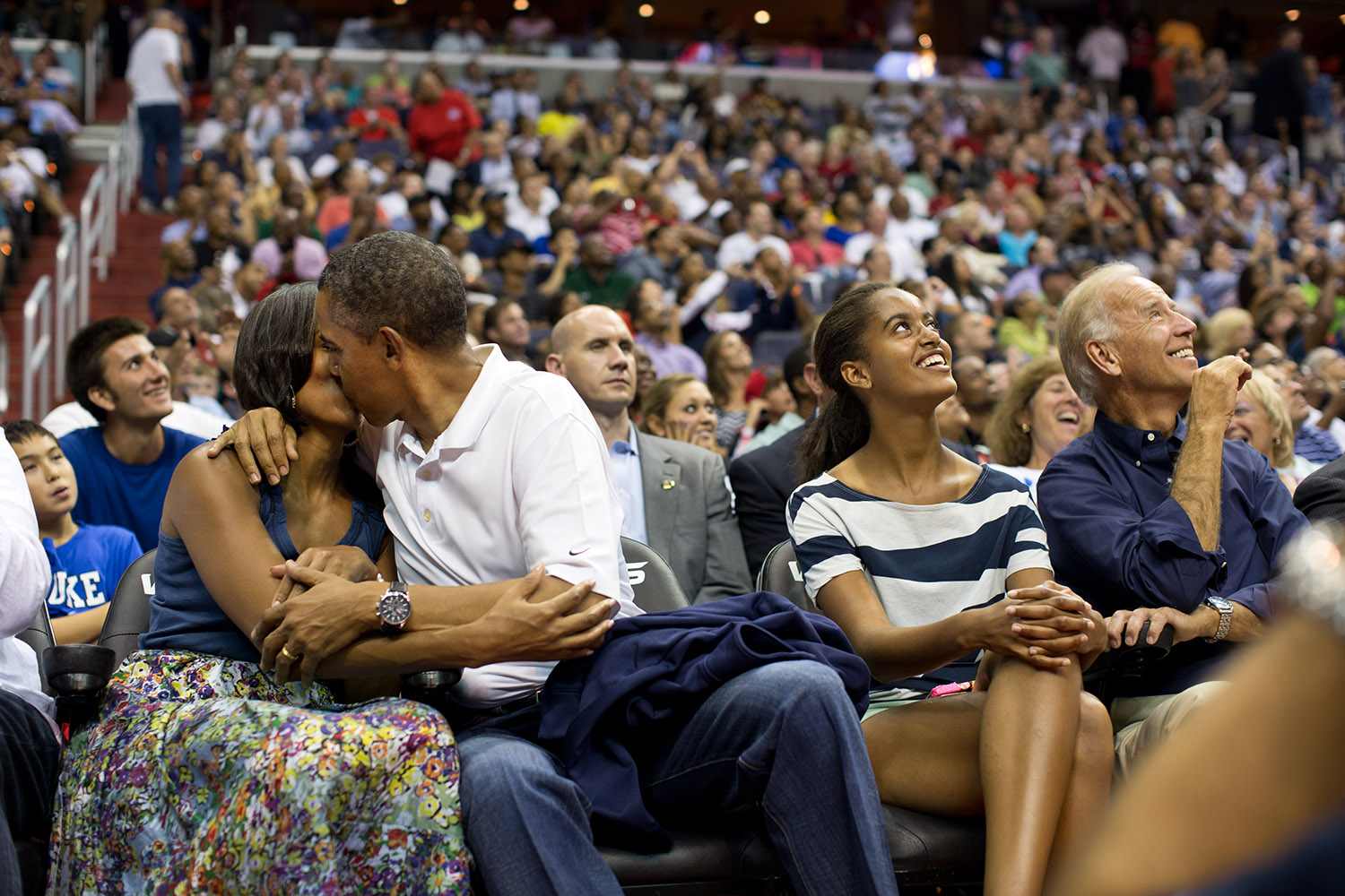 July 16, 2012
"The President and First Lady were attending the game between the U.S. Men's Olympic basketball President Barack Obama and Brazil in Washington, D.C. During the first half, the jumbotron flashed couples on their 'Kiss Cam', where they are then induced by the crowd to kiss each other. But neither the President or First Lady saw themselves when they were flashed on 'Kiss Cam', and some in the audience booed when they didn't kiss. At halftime, as we walked to the locker room to visit the U.S. team, daughters Malia and Sasha were asking their parents why they hadn't kissed during their 'Kiss Cam' moment. Both the President and First Lady said they hadn't even realized what had happened and didn't know why people were booing. So in the second half, when they appeared again on the 'Kiss Cam', the President leaned over to kiss the First Lady amongst audience cheers as Malia and the Vice President watched overhead on the jumbotron." (Official White House Photo by Pete Souza)

This official White House photograph is being made available only for publication by news organizations and/or for personal use printing by the subject(s) of the photograph. The photograph may not be manipulated in any way and may not be used in commercial or political materials, advertisements, emails, products, promotions that in any way suggests approval or endorsement of the President, the First Family, or the White House. 