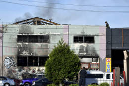 A firefighters walks on the roof of a smoldering building after a fire tore through a warehouse party early Saturday, Dec. 3, 2016 in Oakland.   Oakland fire chief Teresa Deloche-Reed said many people were unaccounted for as of Saturday morning and authorities were working to verify who was in the cluttered warehouse when the fire broke out around 11:30 p.m. Friday. (AP Photo/Josh Edelson)