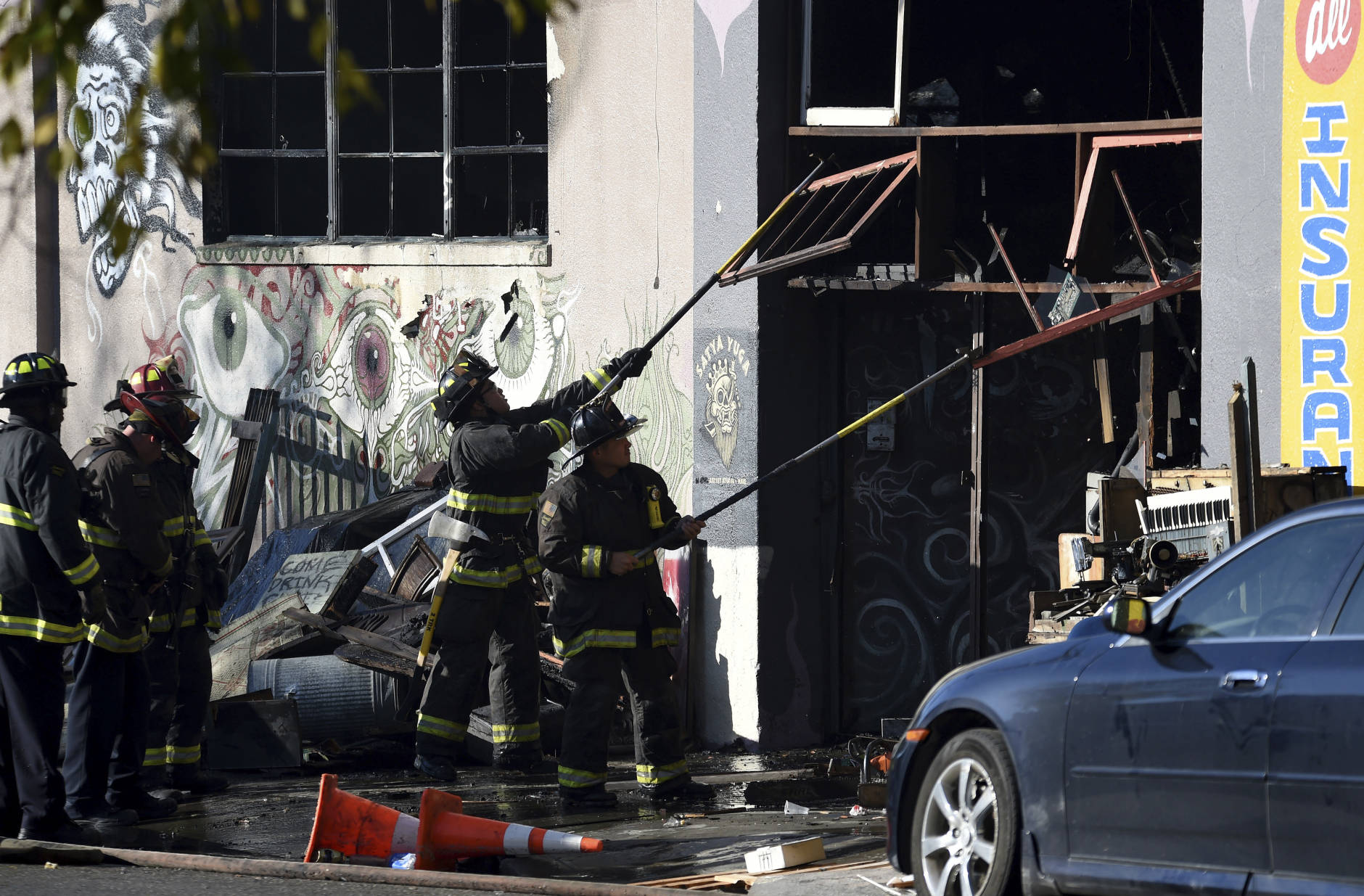 Firefighters clear an entry to a smoldering building after a fire tore through a warehouse party early Saturday, Dec. 3, 2016 in Oakland.   Oakland fire chief Teresa Deloche-Reed said many people were unaccounted for as of Saturday morning and authorities were working to verify who was in the cluttered warehouse when the fire broke out around 11:30 p.m. Friday. (AP Photo/Josh Edelson)