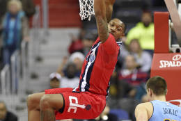 Washington Wizards guard Bradley Beal (3) hangs on the rim after he dunked the ball as Denver Nuggets forward Nikola Jokic, of Serbia, (15) looks on during the first half of an NBA basketball game, Thursday, Dec. 8, 2016, in Washington. (AP Photo/Nick Wass)