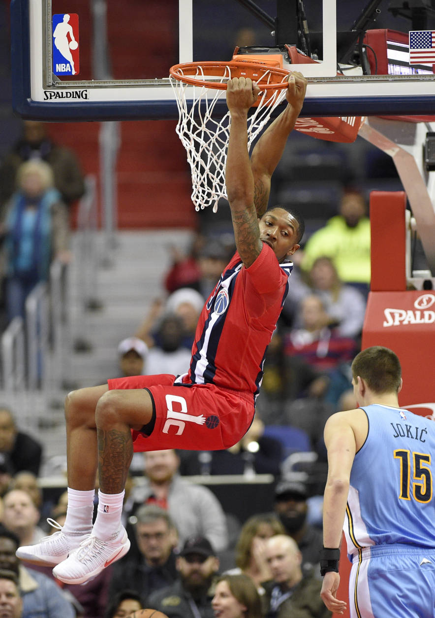 Washington Wizards guard Bradley Beal (3) hangs on the rim after he dunked the ball as Denver Nuggets forward Nikola Jokic, of Serbia, (15) looks on during the first half of an NBA basketball game, Thursday, Dec. 8, 2016, in Washington. (AP Photo/Nick Wass)