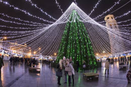 Visitors take a selfie in front of the illuminated Christmas tree at Cathedral square in Vilnius, Lithuania, Tuesday, Dec. 20, 2016. (AP Photo/Mindaugas Kulbis)
