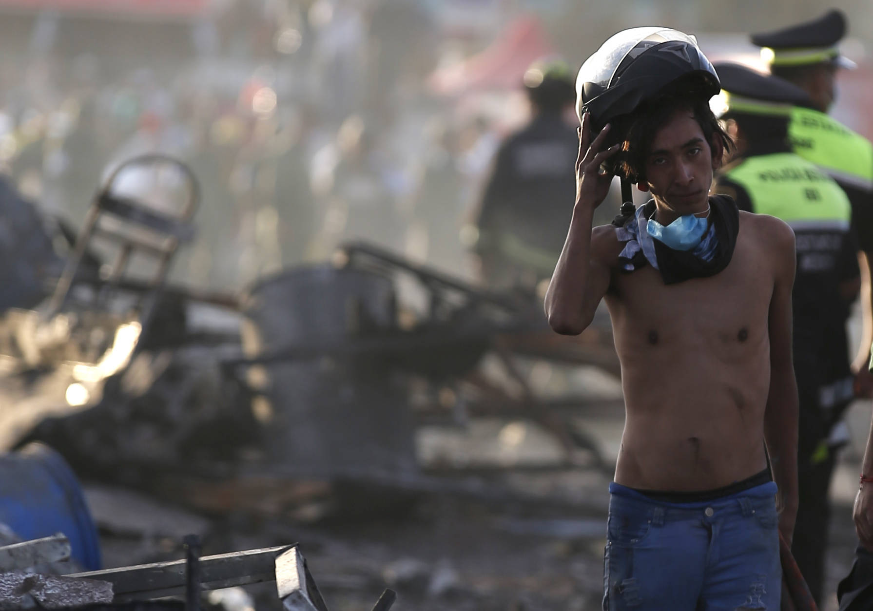 A boy takes his helmet off as he pauses while working at the scorched ground of the open-air San Pablito fireworks market, in Tultepec, outskirts of Mexico City, Mexico, Tuesday, Dec. 20, 2016.  An explosion ripped through Mexico’s best-known fireworks market on the northern outskirts of the capital Tuesday, injuring scores and killing at least 9 people , according to Mexican Federal Police. (AP Photo/Eduardo Verdugo)