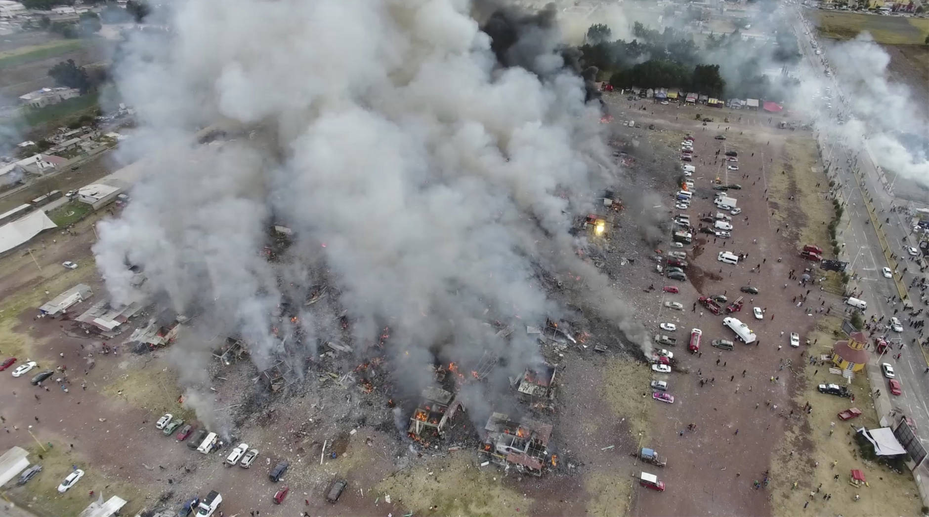 This image made from video provided by APTN, shows a view from a drone of smoke billowing from the San Pablito Market, where an explosion ripped through a fireworks market in Tultepec, Mexico, Tuesday, Dec. 20, 2016. Sirens wailed and a heavy scent of gunpowder lingered in the air after the afternoon blast at the market, where most of the fireworks stalls were completely leveled. According to the Mexico state prosecutor there are at least 26 dead. (Pro Tultepec via APTN)
