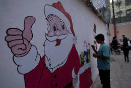 A Christian gives final touches to a mural of Santa Claus in preparation for Christmas celebrations in Karachi, Pakistan, Thursday, Dec. 22, 2016. (AP Photo/Shakil Adil)