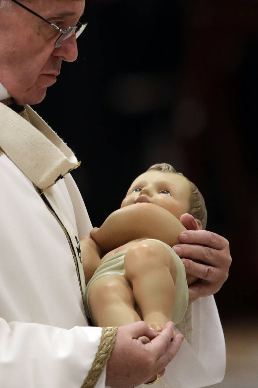 Pope Francis holding a statue of Baby Jesus leaves at the end of the Christmas Eve Mass celebrated in St. Peter's Basilica at the Vatican, Saturday, Dec. 24, 2016. The pontiff urged Christians to celebrate the birth of Jesus by thinking about the plight of today's children, bemoaning how they're forced to hide to escape bombs or flee in a migrant boat or how they’re prevented from being born entirely. (AP Photo/Alessandra Tarantino)
