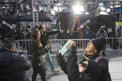 Visitors to Times Square take photos as technicians prepare a stage that will be used in the New Years celebration, Friday, Dec. 30, 2016, in New York's Times Square. (AP Photo/Mary Altaffer)