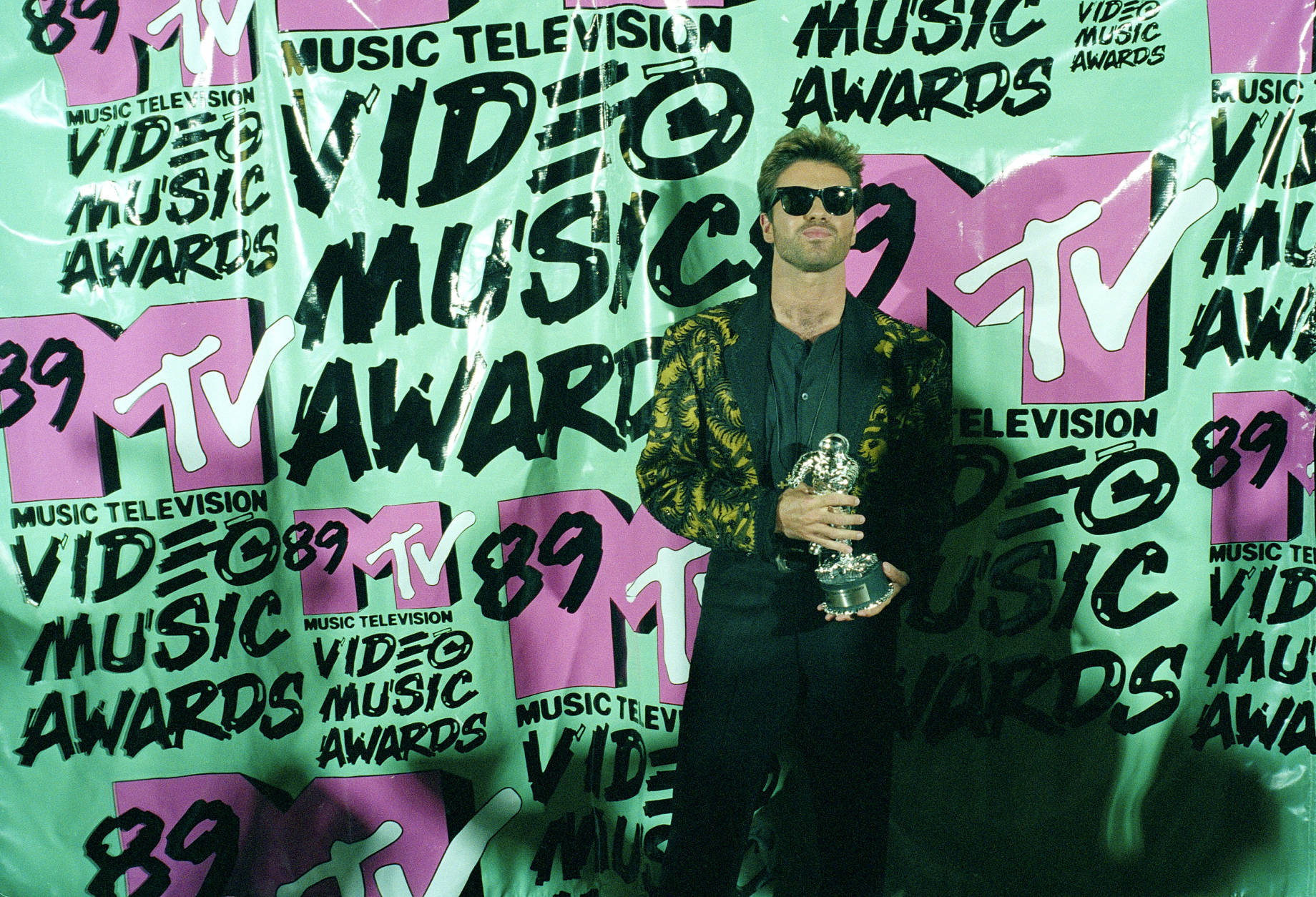 Pop singer George Michael displays his trophy after winning the 1989 Video "Vanguard Award" for his "Father Figure" video during the MTV Music Awards Wednesday, Sept. 6, 1989 at the Universal Amitheatre in Universal City, Calf. (AP Photo/Alan Greth)