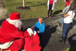 Santa hands a bag of toys to a boy in Upper Marlboro, Md. on Sunday, Dec. 25. 2016. Police say he and his brother were victims of domestic violence. The boys were reunited with their rescuer on Sunday. (WTOP/John Domen)