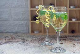 Spritzer cocktail with white wine, mint and ice, decorated with spiral lemon zest, horizontal, copy space