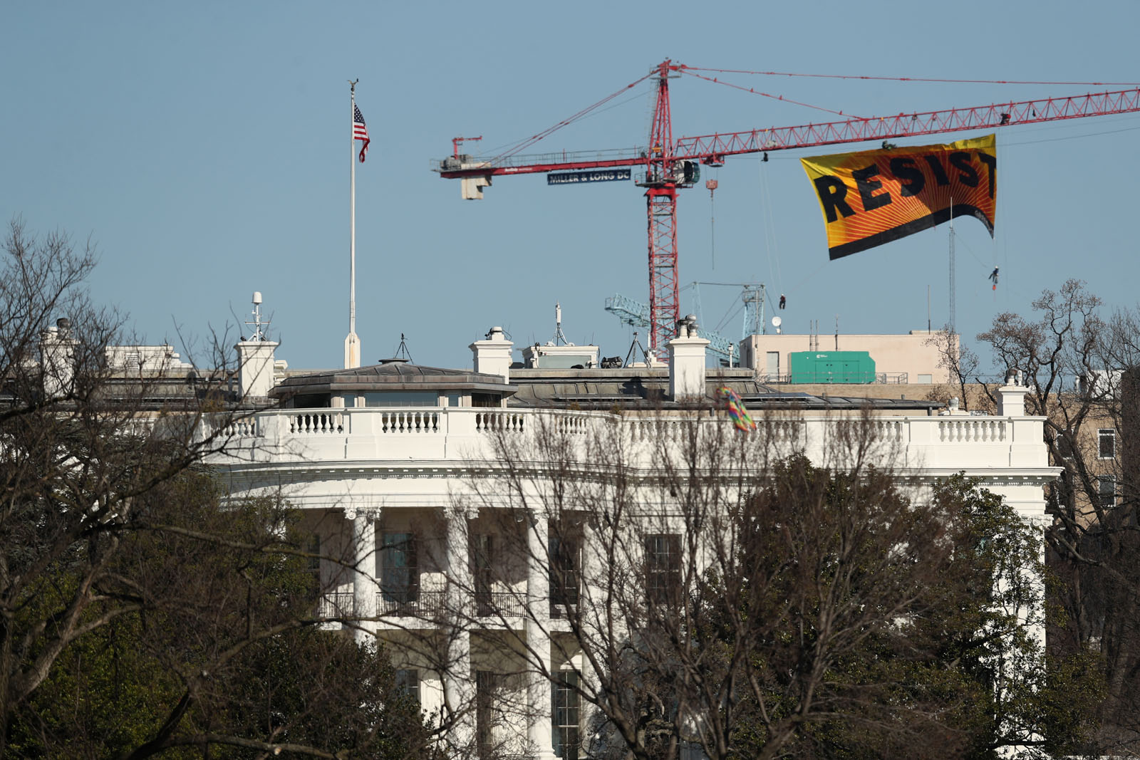 Greenpeace protesters unfurl a banner that reads "Resist" at the construction site of the former Washington Post building, near the White House in Washington, Wednesday, Jan. 25, 2017, after police say protesters climbed a crane at the site refusing to allow workers to work in the area. (AP Photo/Andrew Harnik)