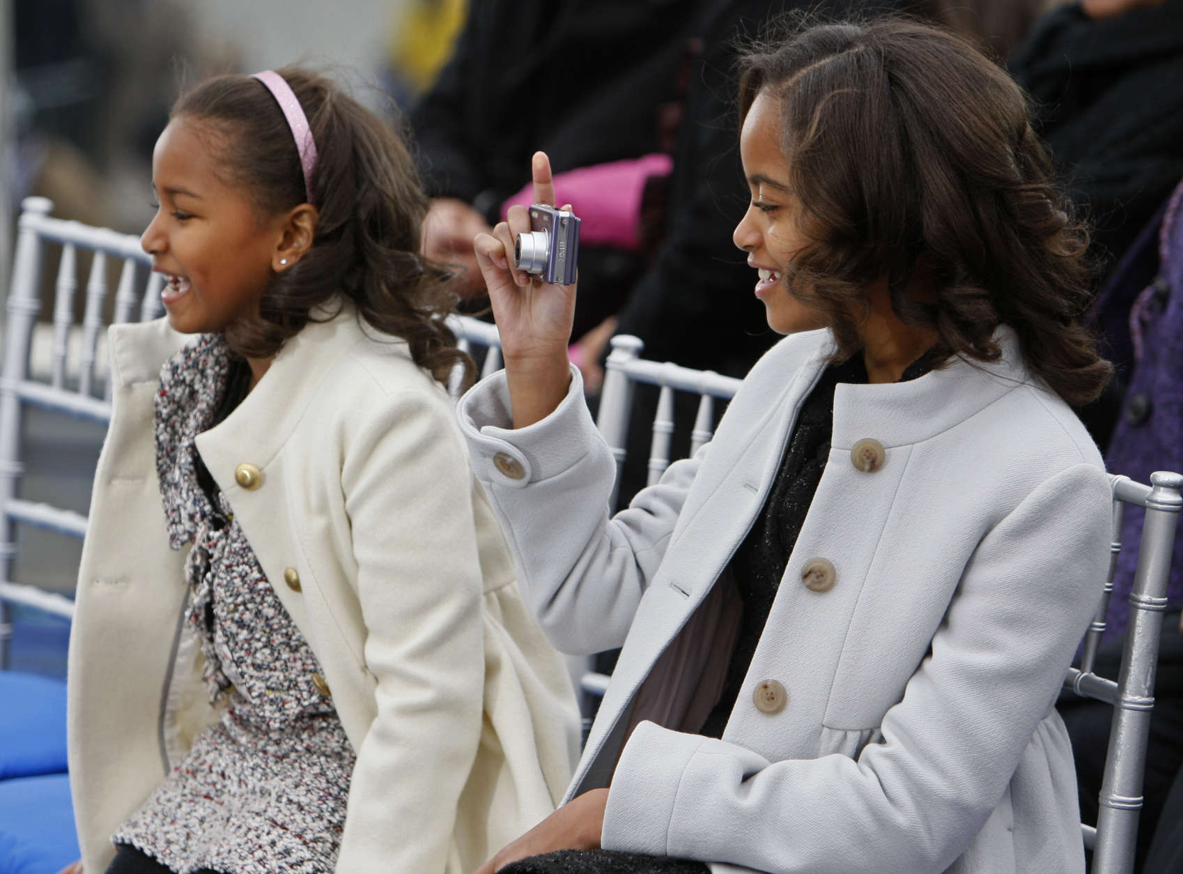 Malia Obama, 10, right, takes a picture as she sits next to her sister Sasha before their parents, President-elect Barack Obama and Michelle Obama, arrive onstage at the Lincoln Memorial inaugural concert Sunday, Jan. 18, 2009. (AP Photo/Charles Dharapak)